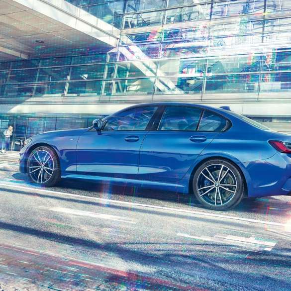 BMW 3 Series Sedan, side view Still shot of the BMW 3 Series Sedan from the side on the day in front of a glass building.