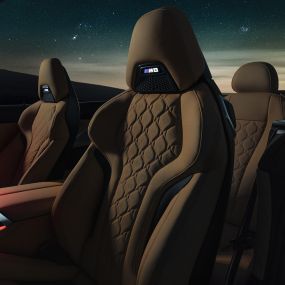 Спортивные сиденья в коже 'Merino'. BMW M8 Competition Кабриолет с открытой мягкой крышей под звездным небом, салон со спортивными сиденьями M из кожи 'Merino' и красным фоновым освещением.