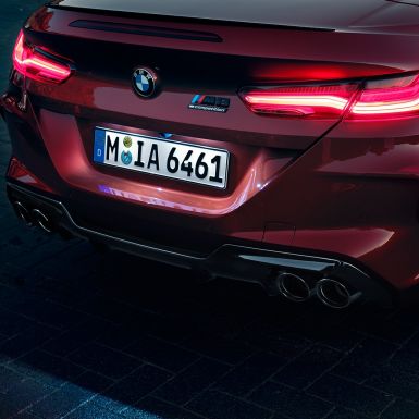BMW M8 Competition Кабриолет, задняя часть. BMW M8 Competition Кабриолет в Motegi Red металлик, задняя часть со светодиодными задними фарами и значком M8 Competiton.