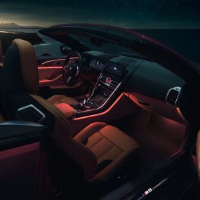 BMW M8 Competition Convertible, interior. BMW M8 Competition Convertible with open softtop, interior with red ambient light at night.