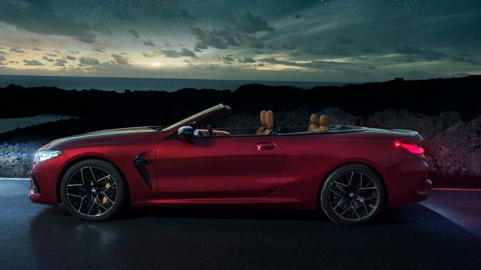 BMW M8 Competition Convertible, side view. BMW M8 Competition Convertible in Motegi Red metallic with open softtop, side view, standing at night under starry sky.