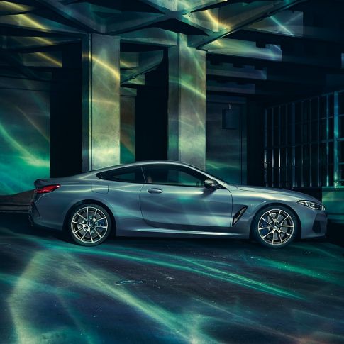 BMW M850i xDrive Coupé, вид сбоку. BMW M850i xDrive Coupé в Barcelona Blue металлик, вид сбоку, перед зданием.