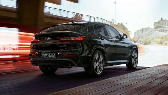 BMW X4 M40i и BMW X4 M40d, вид сзади с поворотом в три четверти. BMW X4 M40i и BMW X4 M40d в Black Sapphire металлик, за рулем, экстерьер, вид сзади с поворотом в три четверти со световыми полосками.