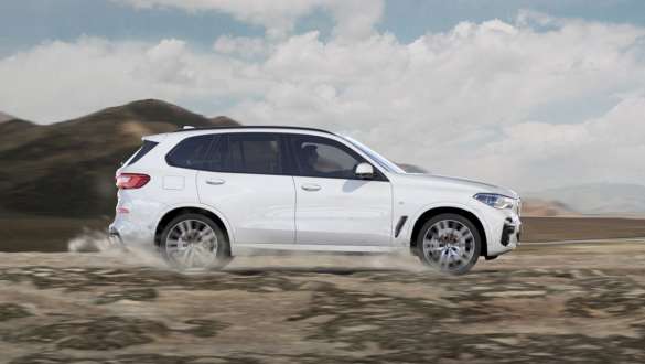 Режим вождения BMW X5 xGravel Режим вождения xGravel BMW X5 G05 2018 Mineral White металик, вид сбоку при движении на сыпучей, каменистой поверхности.