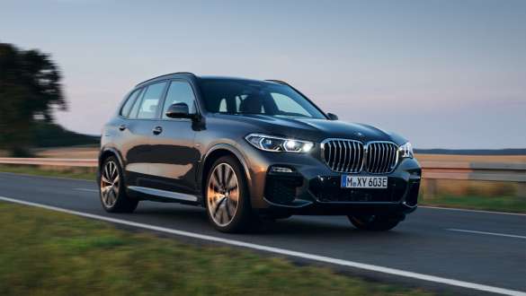 Плагин-гибрид BMW X5 xDrive45e G05, вид спереди на три четверти во время езды Плагин-гибрид BMW X5 xDrive45e G05, вид спереди на три четверти во время езды по улице