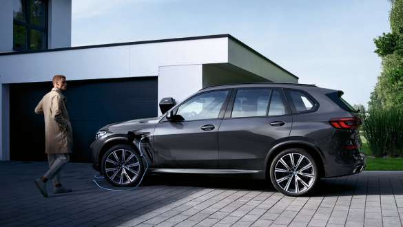 Плагин-гибрид BMW X5 xDrive45e G05, вид сбоку перед гаражом Плагин-гибрид BMW X5 xDrive45e G05, вид сбоку перед гаражом с моделью