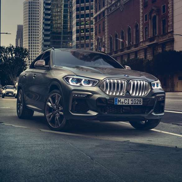 Адаптивная подвеска BMW X6 M Professional. BMW X6, передняя часть с поворотом в три четверти перед городской обстановкой.