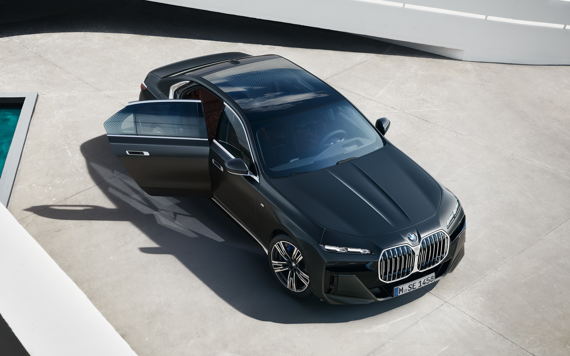 Вид с высоты птичьего полета на BMW 7 серии Седан G70 ICE с пакетом 740i M Sport в цвете Frozen Deep grey metallic BMW 7 серии Седан G70 ICE 740i с пакетом M Sport в цвете Frozen Deep grey metallic, вид с высоты птичьего полета с открытой пассажирской дверью
