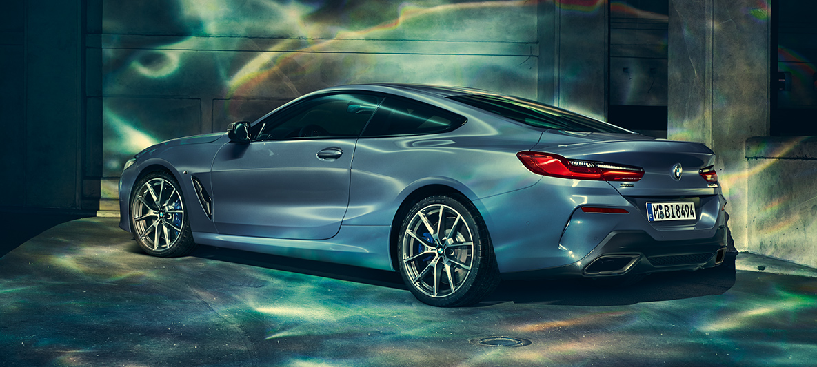 BMW 8 Series Coupé, three-quarter rear shot Three-quarter rear shot of the BMW 8 Series Coupé at night in front of an urban setting.