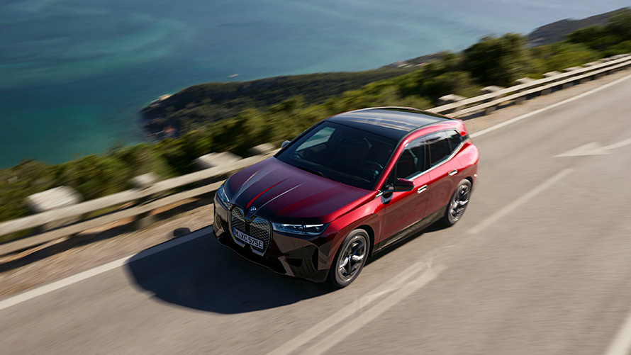 Электрический SUV BMW iX i20 xDrive50, мощность Электрический SUV BMW iX i20 2021 xDrive50 цвета Aventurin Red едет по улице, мощность