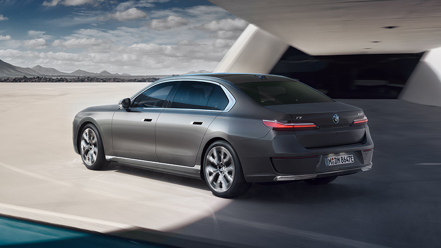 BMW i7, вид три четверти сзади BMW i7 Седан G70 BMW Individual Oxid grey metallic, вид три четверти на фоне здания