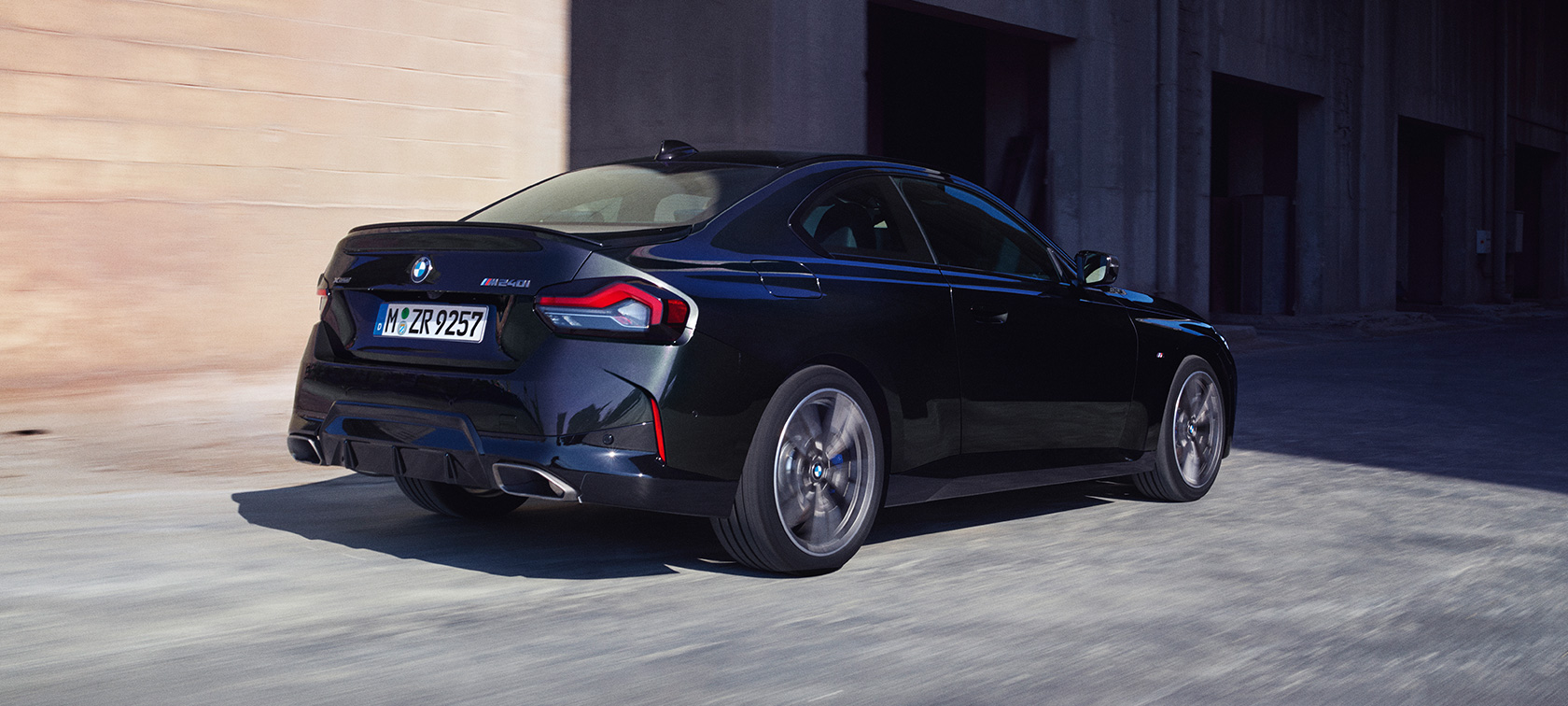 Вид сзади в три четверти BMW M240i xDrive Coupe G42 2021 BMW M240i xDrive Coupe G42 2021 "Черный Сапфир металлик", вид сзади в три четверти в движении