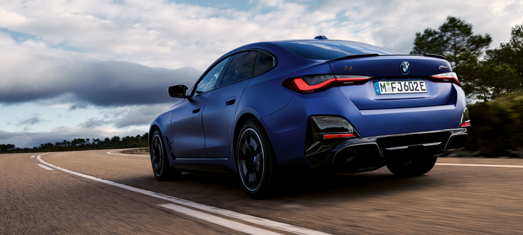 Вид сзади в три четверти BMW i4 M50 G26 2021 BMW i4 M50 G26 2021 "Морозный Синий Портимау металлик" BMW Individual, вид сзади в три четверти в движении