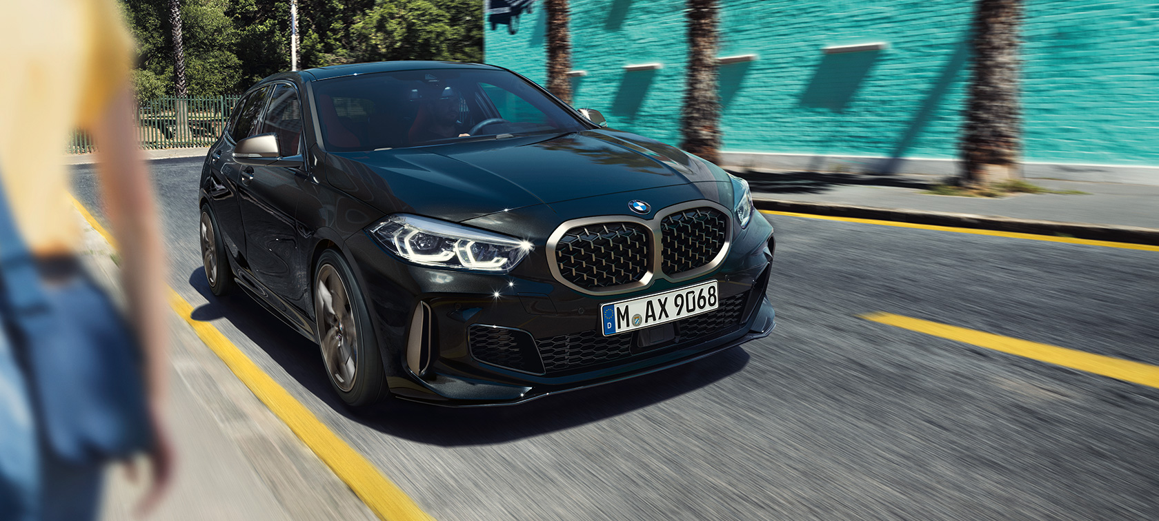 BMW M135i xDrive в Black Sapphire металлик, вид спереди за рулем с поворотом в три четверти.