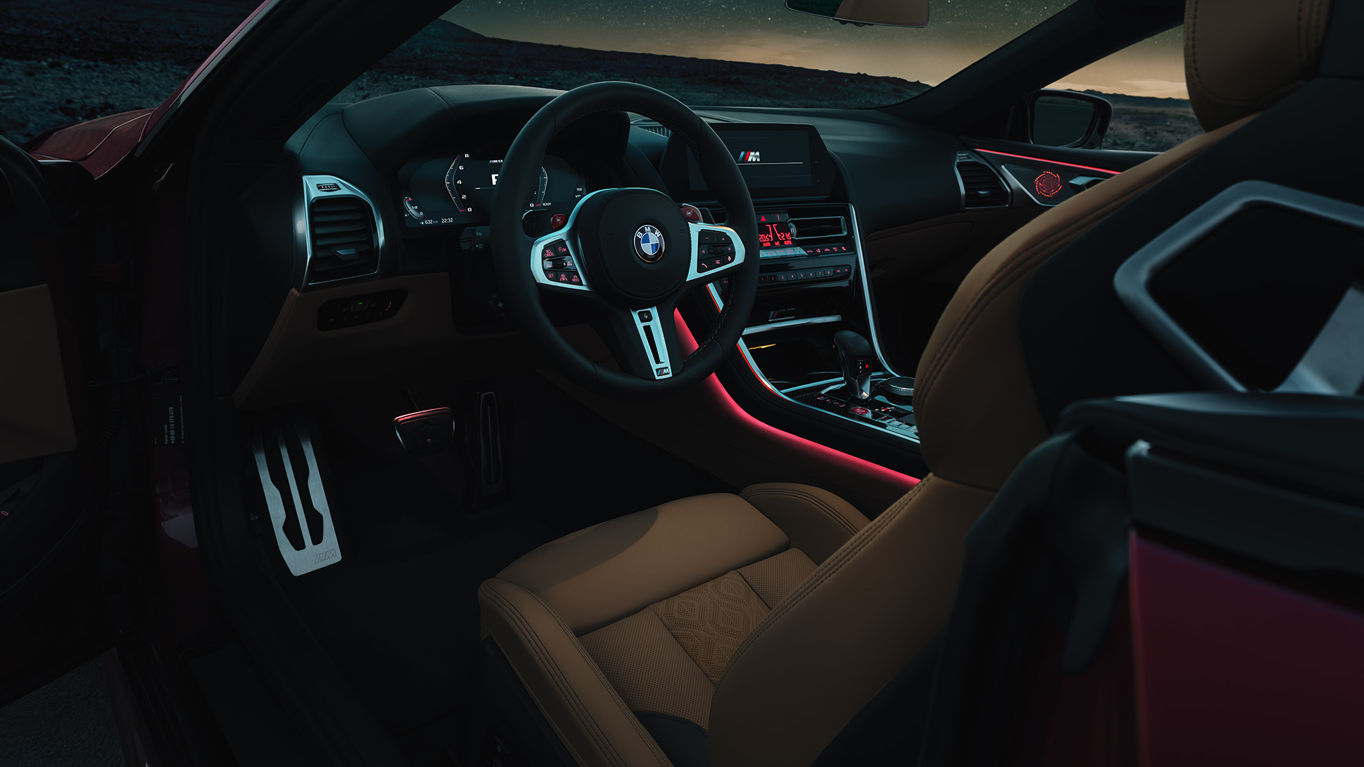 BMW M8 Competition Кабриолет, кабина. BMW M8 Competition Кабриолет, кабина ночью с кожаным рулевым колесом M и красным фоновым освещением.