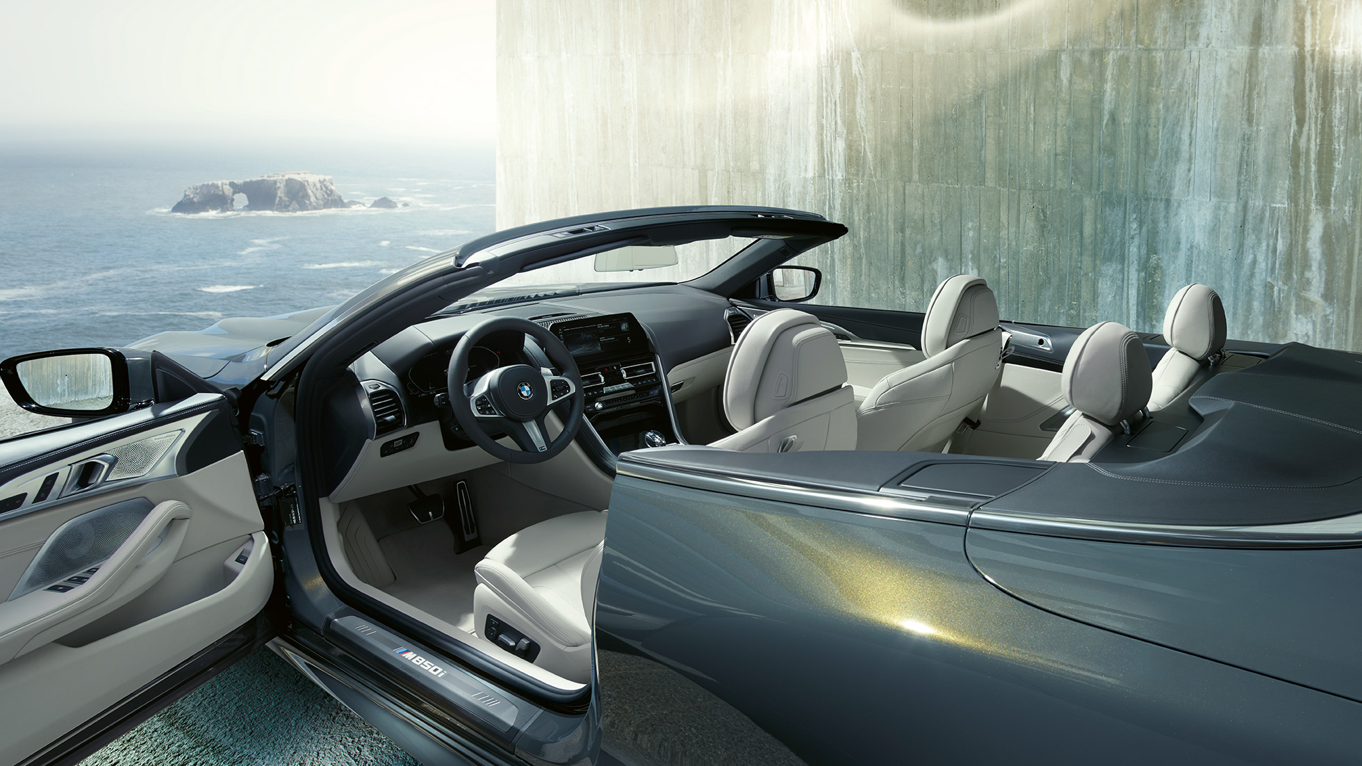 BMW M850i xDrive Кабриолет, салон. BMW M850i xDrive Кабриолет в Dravit Grey металлик с открытым мягким верхом, салон с кожаным рулевым колесом M и отделкой BMW Individual из кожи "Merino" цвета слоновой кости.