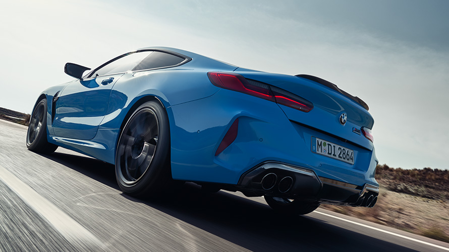 BMW M8 Competition Coupé F92 LCI (рестайлинг 2022 года), вид сзади с поворотом в три четверти, в движении BMW M8 Competition Coupé F92 LCI (рестайлинг 2022 года) Синий Дейтона-Бич, вид сзади с поворотом в три четверти