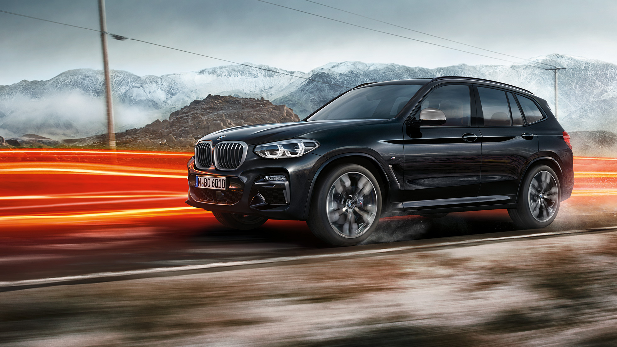 BMW X3 M40i and BMW X3 M40d, side view. BMW X3 M40i and BMW X3 M40d in Black Sapphire metallic, driving, exterior, side view in front of mountain scenery with light strips.