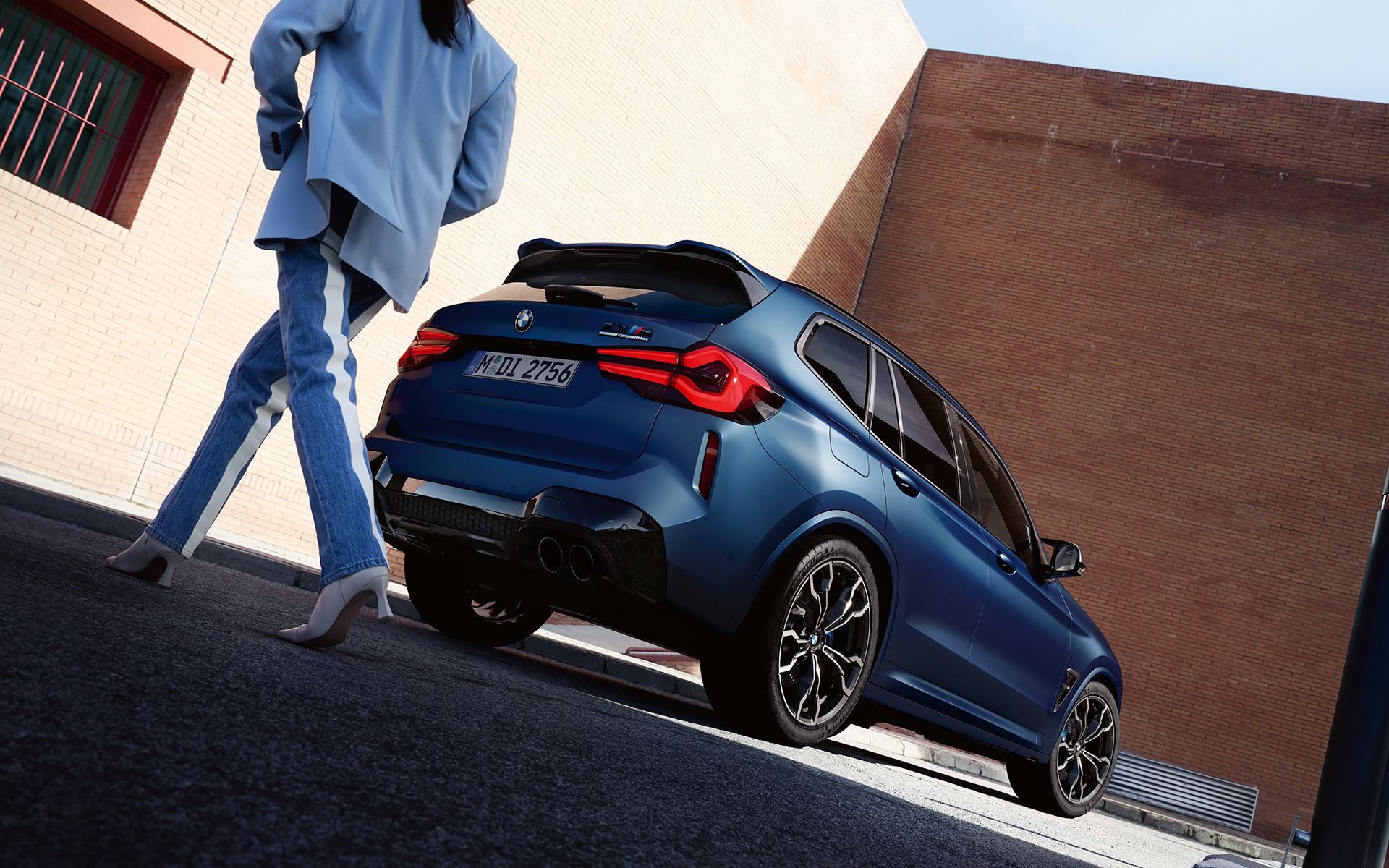 BMW X3 M Competition F97 LCI Facelift 2021 в цвете Frozen Marina Bay Blue металлик, вид сзади в три четверти, снимок с низкого угла с моделью