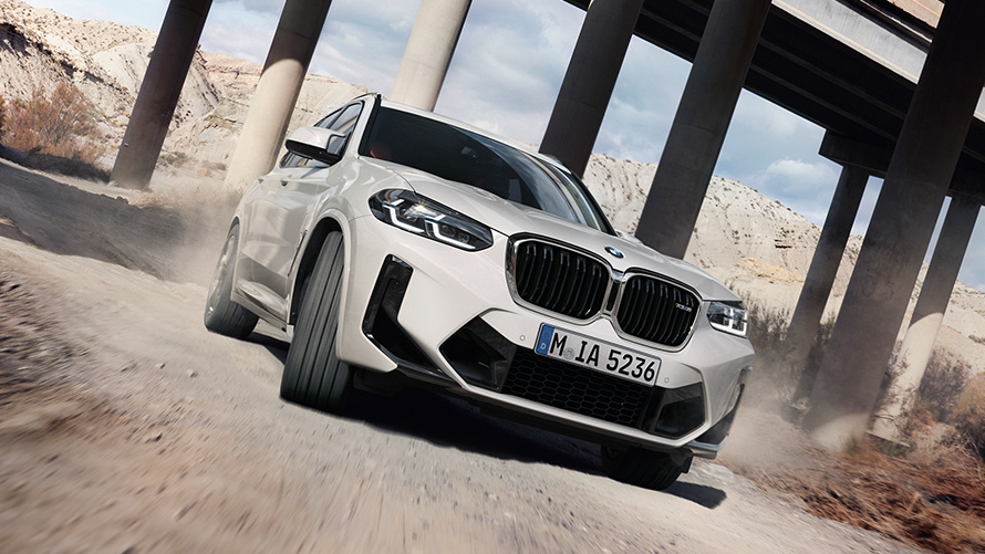 BMW X3 M F97 LCI Facelift 2021 в цвете Alpine White, вид спереди в три четверти на повороте BMW X3 M F97 LCI Facelift 2021 в цвете Alpine White, вид спереди в три четверти на повороте