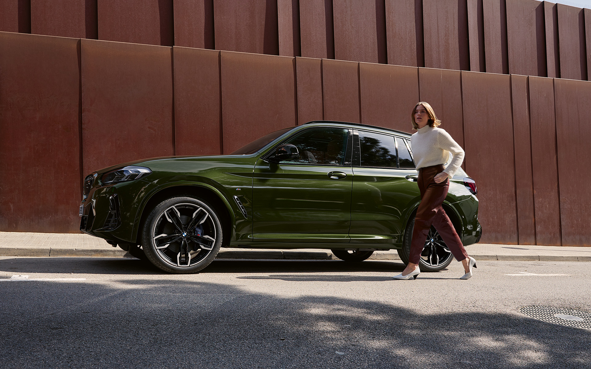 BMW X3 M G01 LCI Facelift 2021 в цвете Malachite Green металлик, вид сбоку с моделью-женщиной