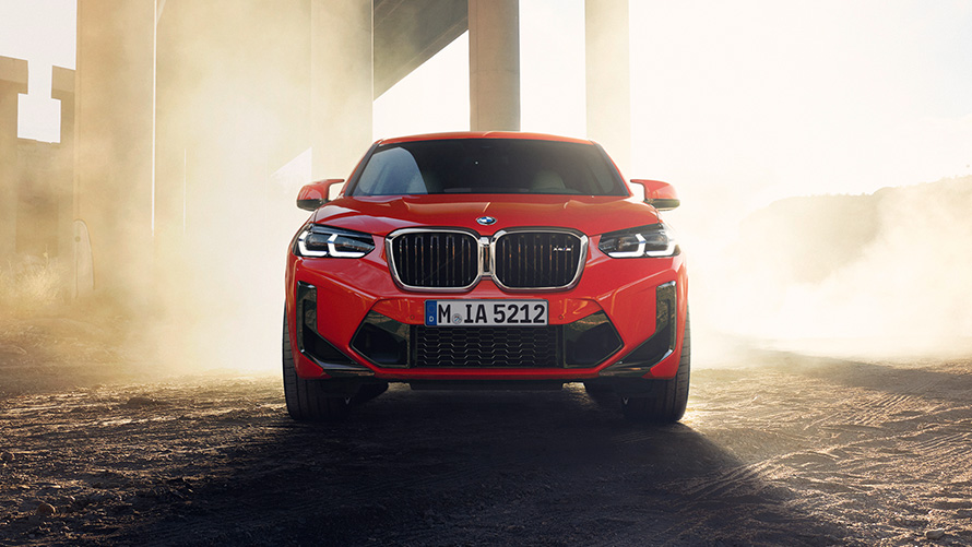 BMW X4 M F98 LCI Facelift 2021 в цвете Toronto Red металлик, вид спереди перед колоннами моста