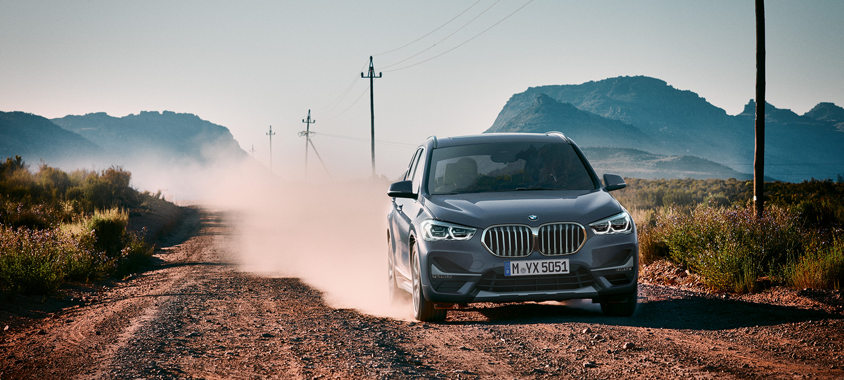 BMW X1, вид сзади с поворотом в три четверти. BMW X1, вид сзади с поворотом в три четверти на фоне горного пейзажа.