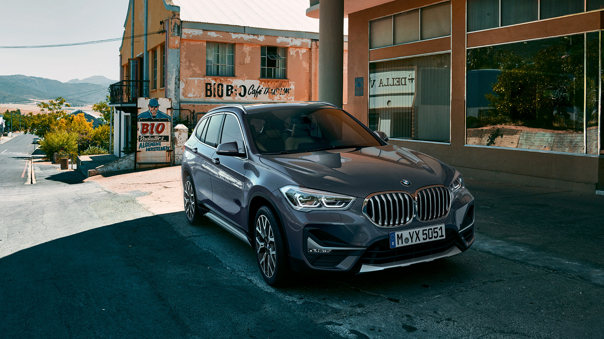 BMW X1, вид спереди с поворотом в три четверти. BMW X1, вид спереди с поворотом в три четверти на фоне городского пейзажа.