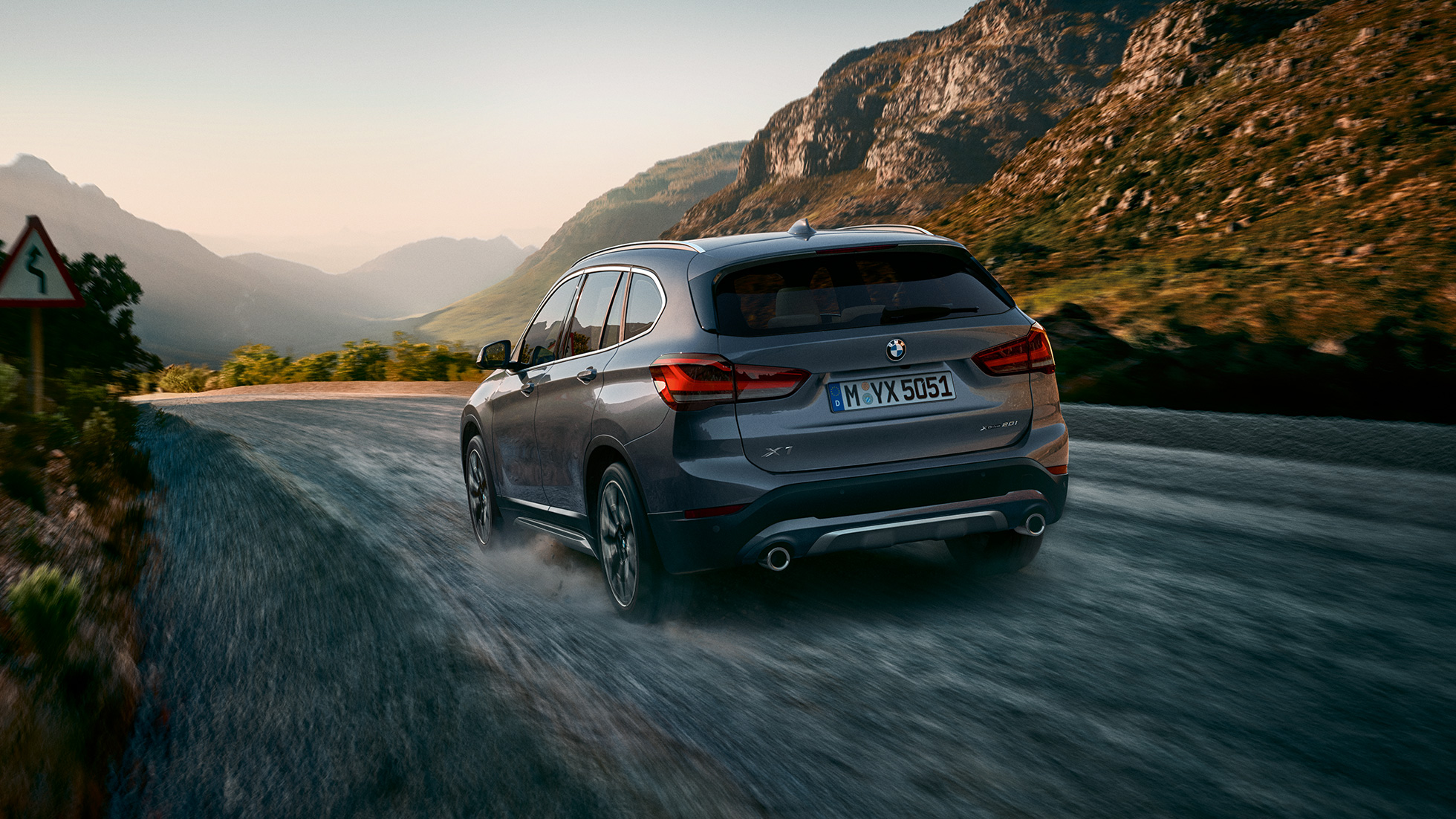 BMW X1, вид сзади с поворотом в три четверти. BMW X1, вид сзади с поворотом в три четверти на фоне горного пейзажа.